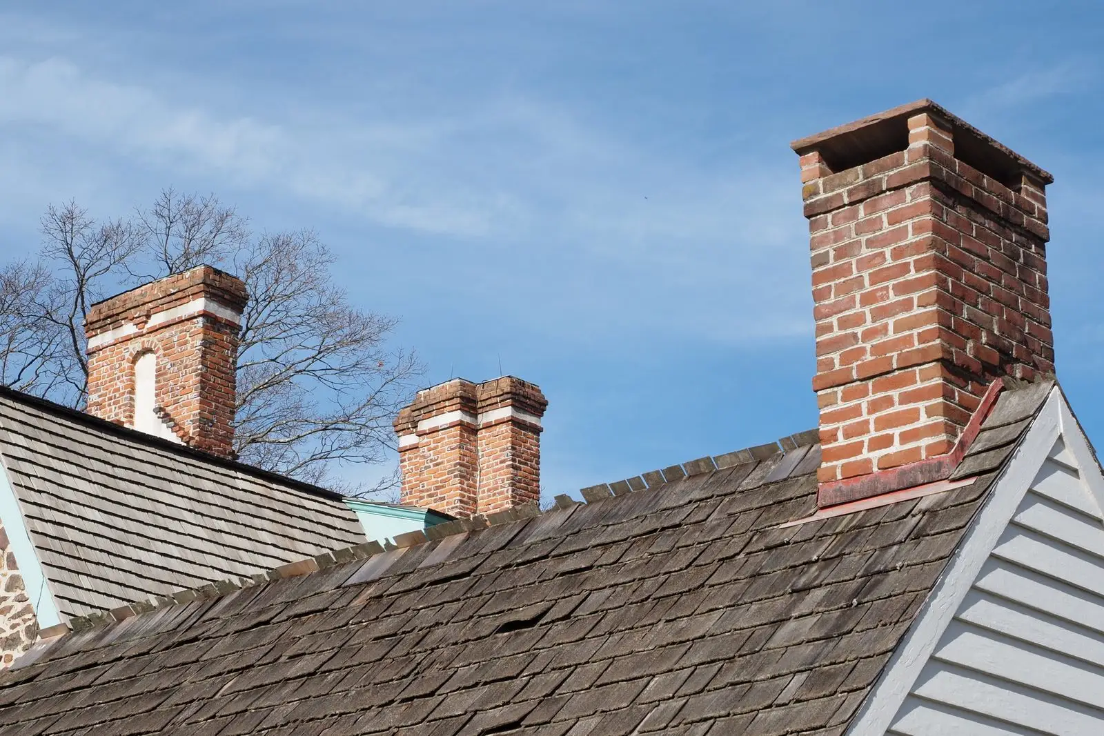 Red brick chimneys rising above a slate roof against a blue sky
