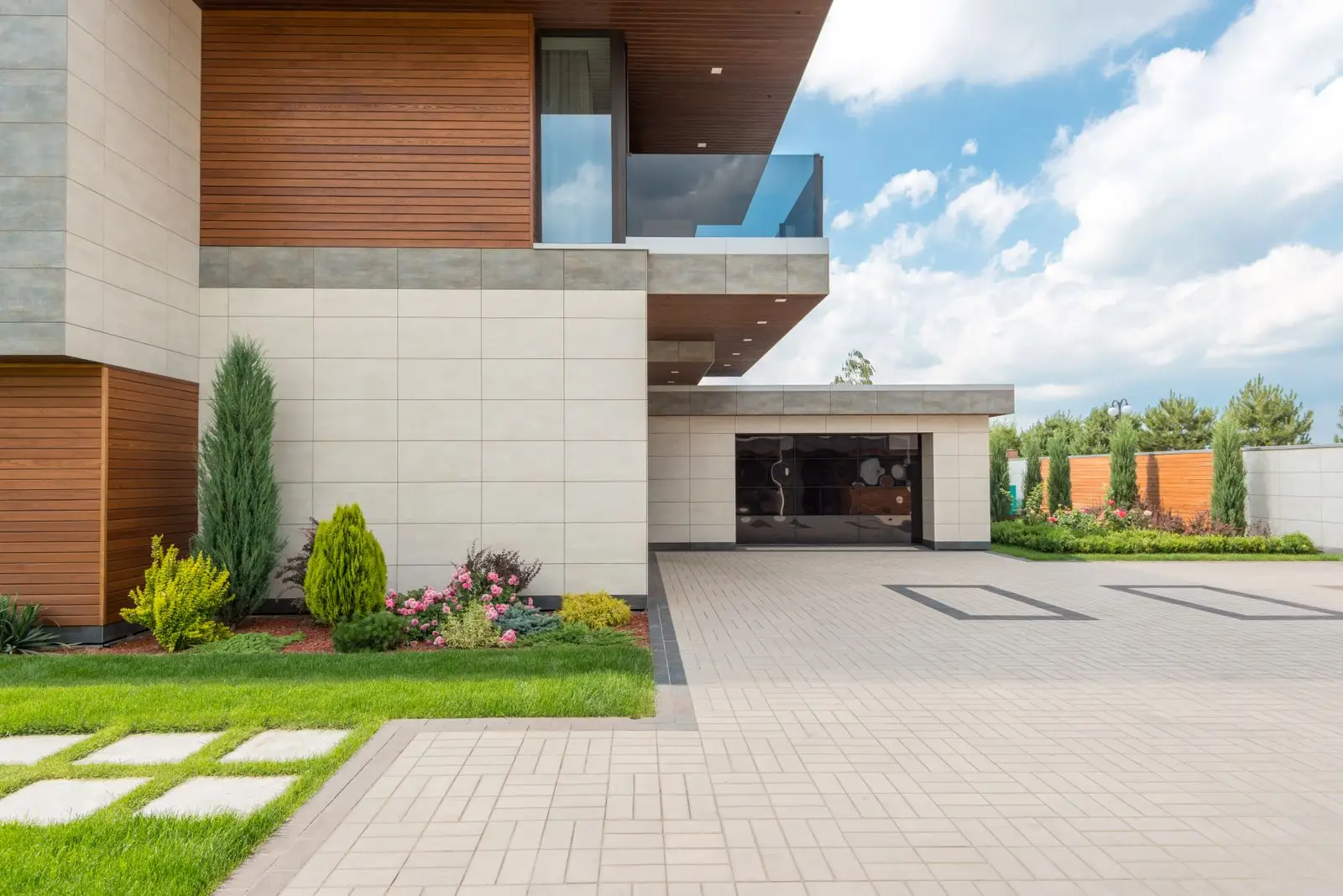 Wide finished concrete driveway leading to a house with planted borders