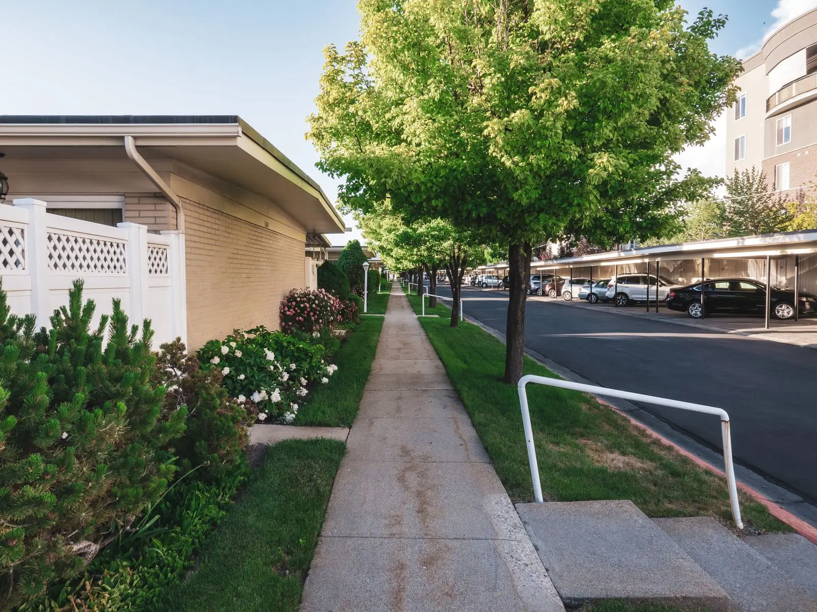Poured concrete walkway running past a house with a handrail