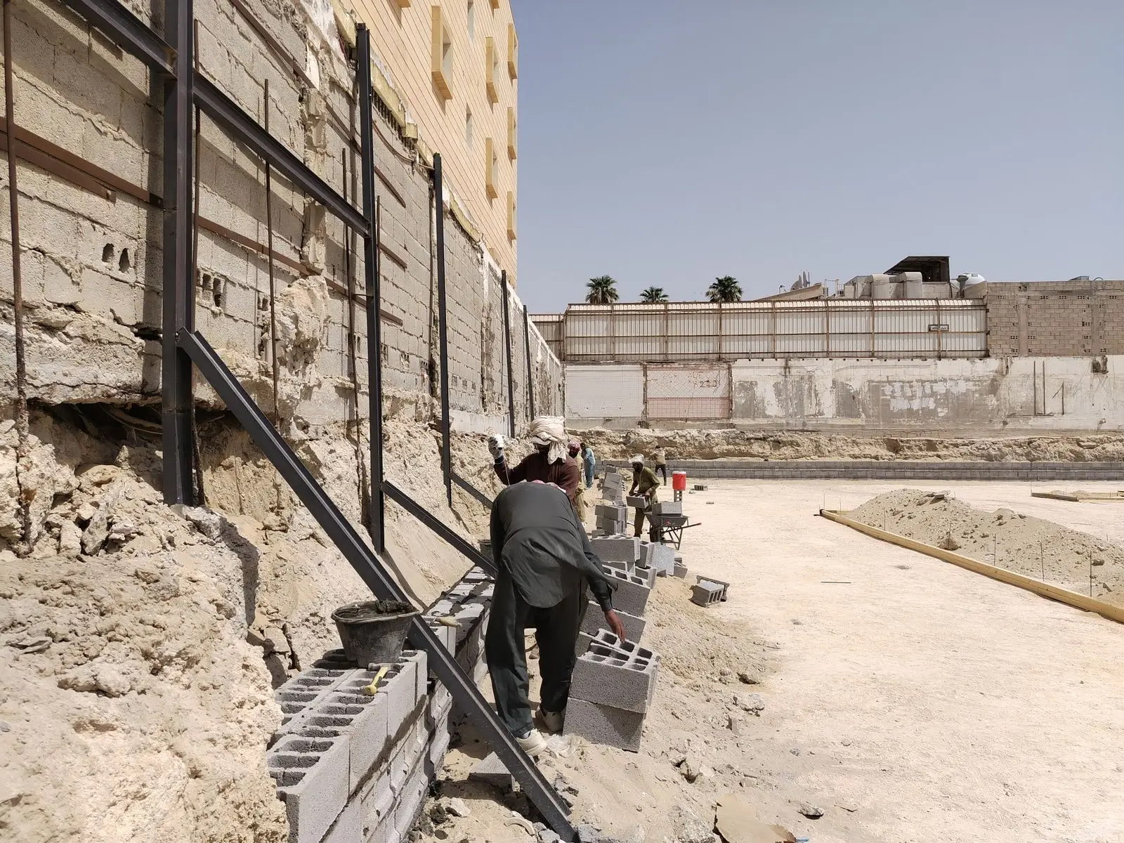 Crew laying a concrete block retaining wall on a compacted base