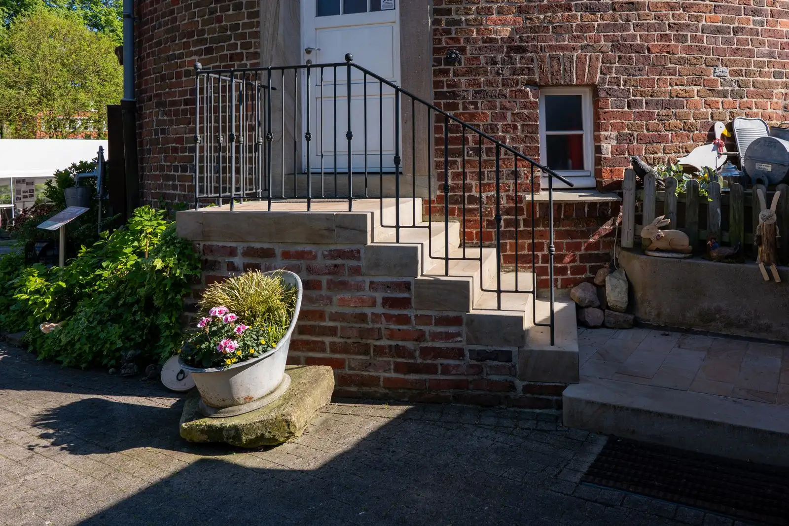 Finished brick entrance steps with a painted handrail and planted pots